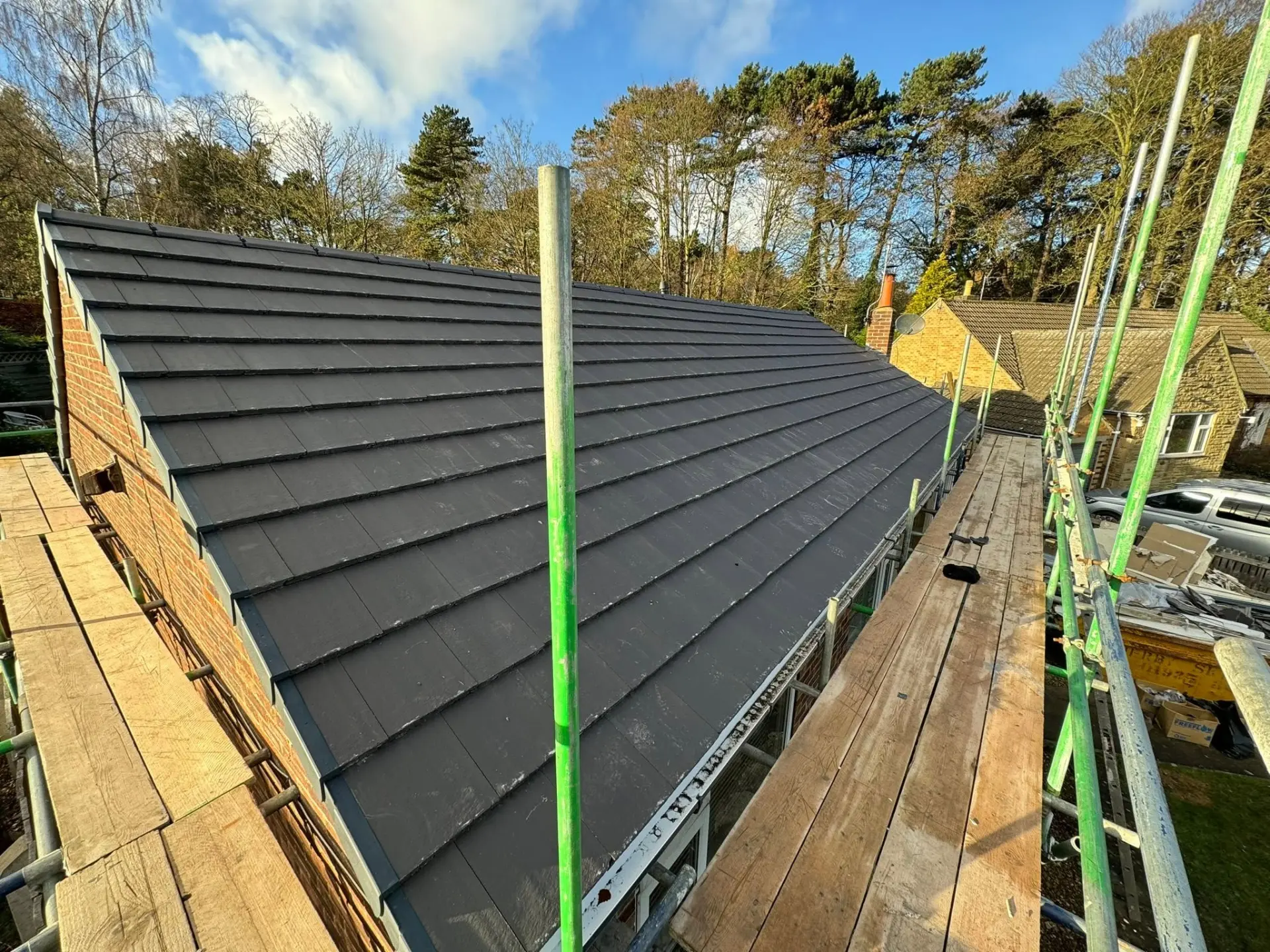 Elevated side view of a large slanted roof with new dark grey tiles