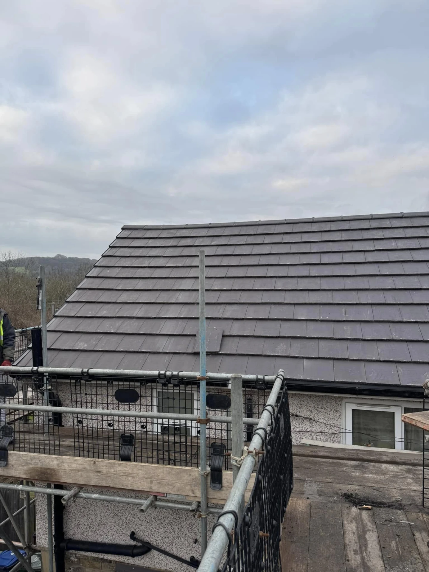Close-up of newly installed dark grey tiles viewed from scaffolding